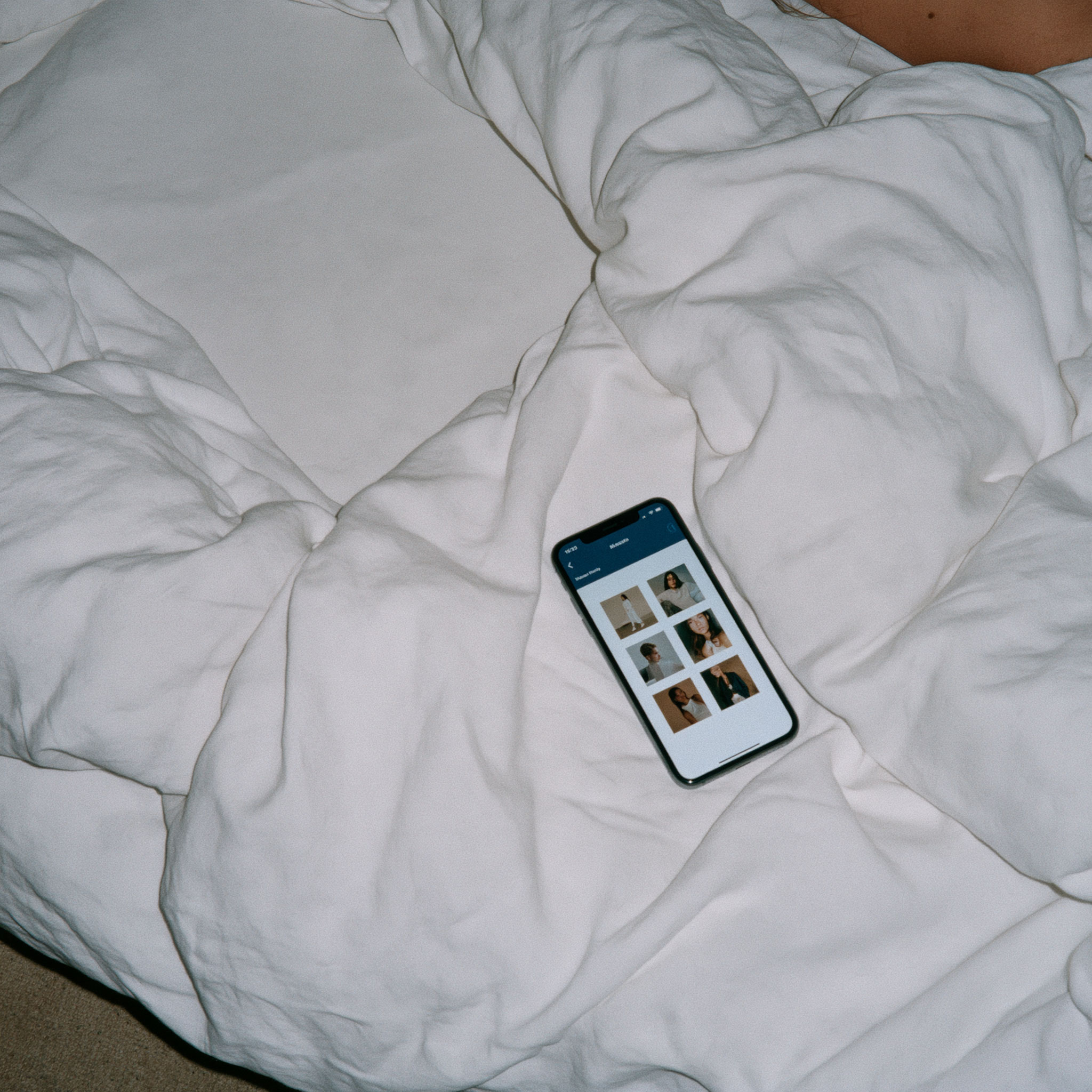 Smartphone displaying a photo gallery on white bedding